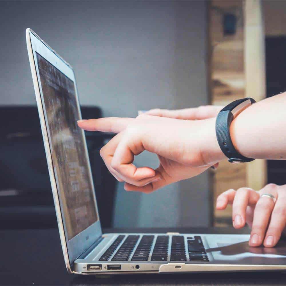 People working off a laptop pointing at the screen