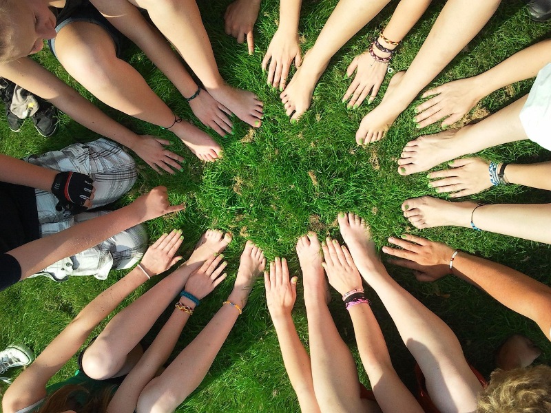 Group of diverse hands joined together in a circle representing community.