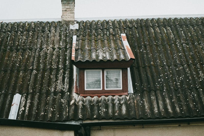 Close-up view of an old asbestos sheet roof on an industrial building.