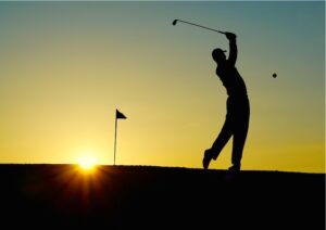 Golfer swinging a club on a green course at Bicester Hotel Golf & Spa.