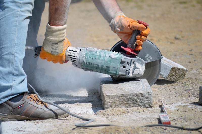 Worker cutting a slab of granite stone with a circular saw.