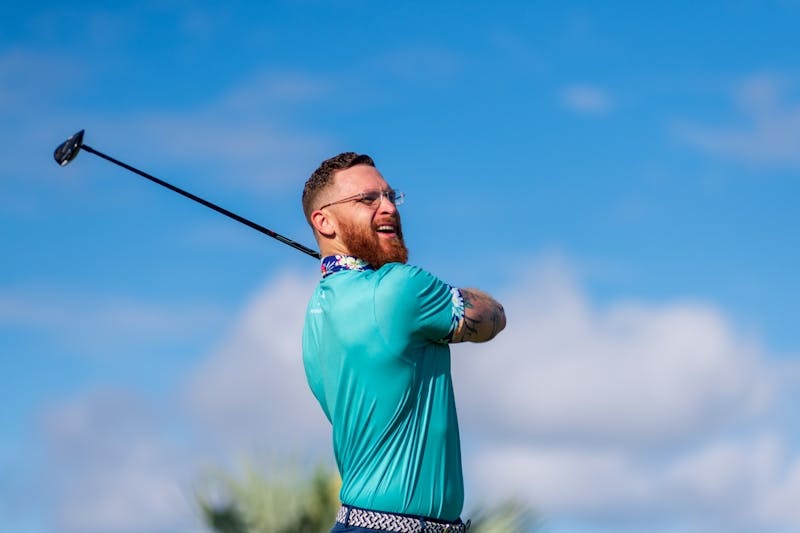 Golfer in mid-swing on a clear day with blue sky.