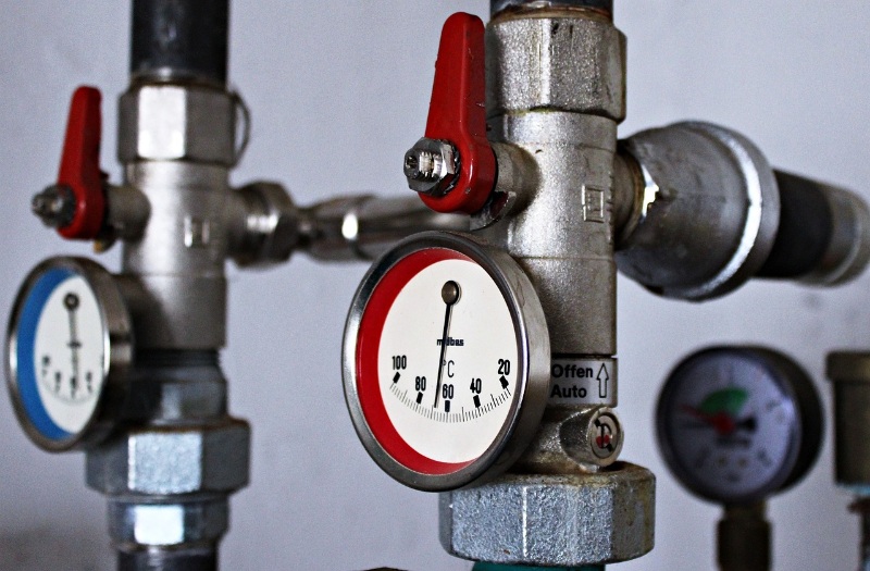 Industrial heating pipework system with gauges and valves in a mechanical room.