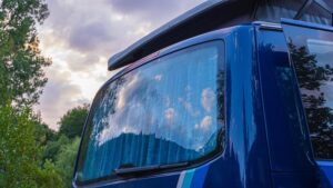 Campervan parked on a scenic coastal road at sunset.