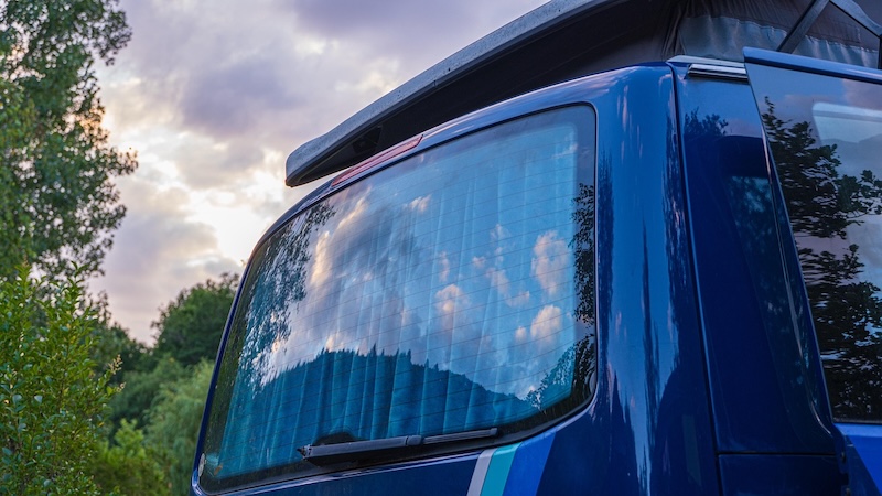Campervan parked on a scenic coastal road at sunset.