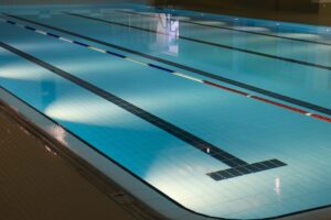 Indoor swimming pool with lanes and bright natural lighting.