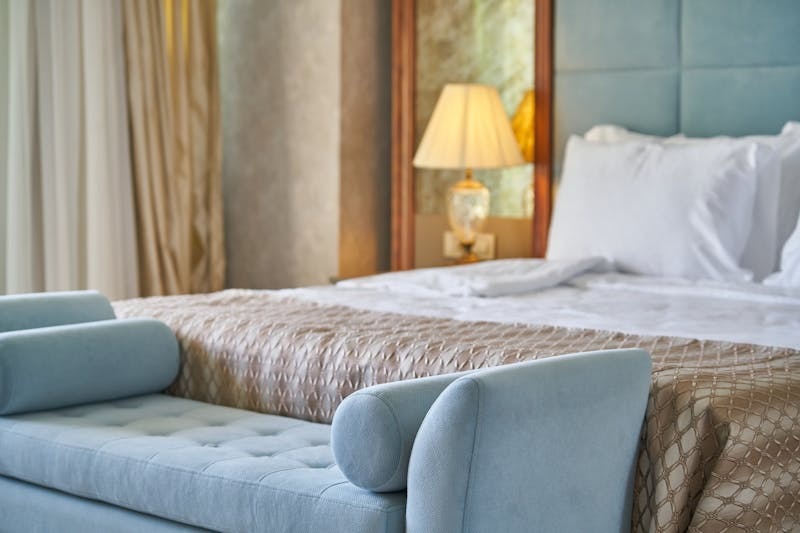 Modern hotel bedroom with a neatly made double bed and soft lighting.
