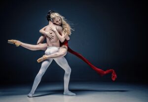 Ballet dancer performing on stage in a dramatic spotlight.