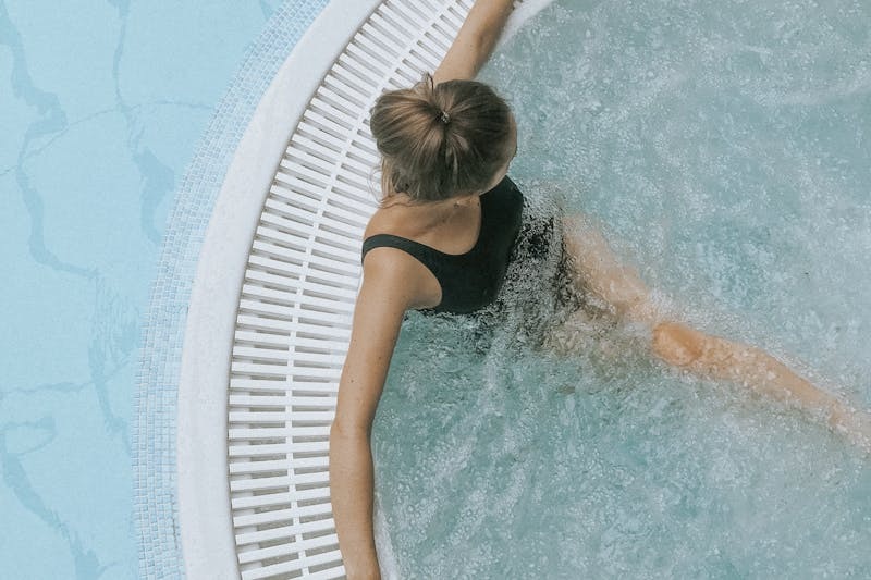 Person relaxing in a bubbling outdoor jacuzzi hot tub.