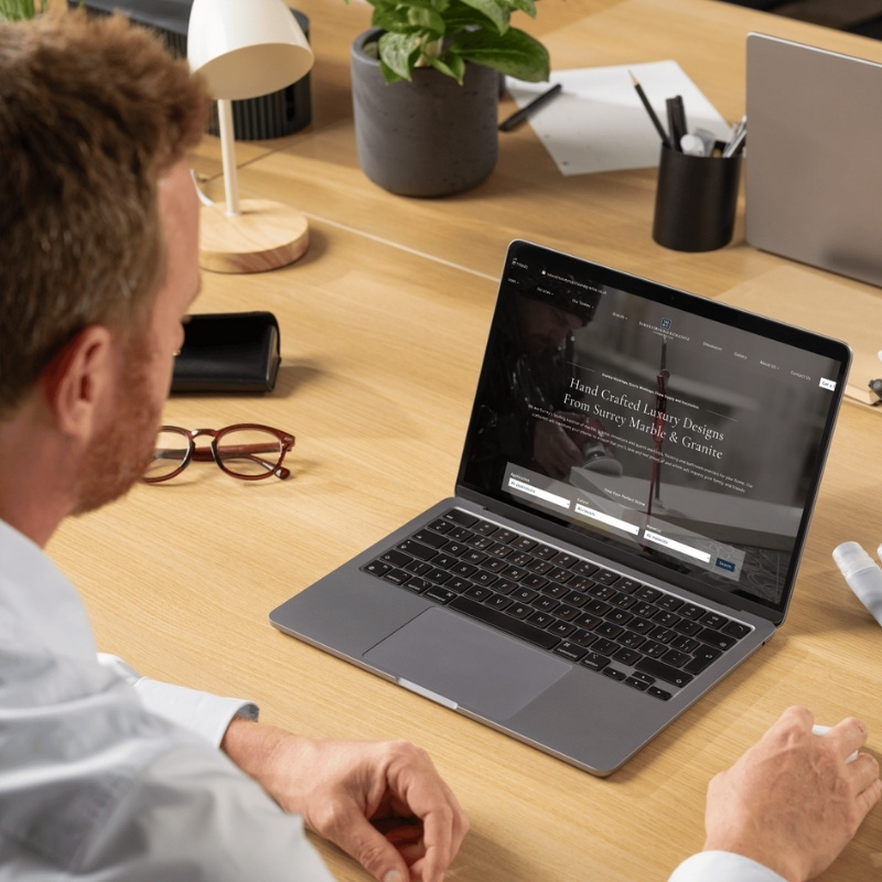 Laptop mockup showcasing the Surrey Marble & Granite website homepage.