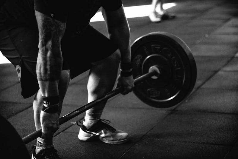 Man performing a deadlift with a loaded barbell in a gym.