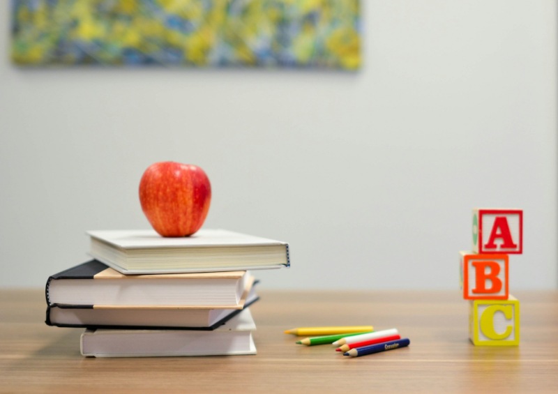 Stack of school textbooks with colourful pencils on top.