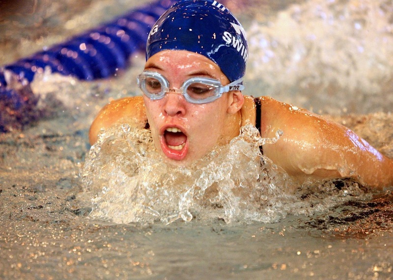 Competitive swimmer performing the butterfly stroke in a pool.