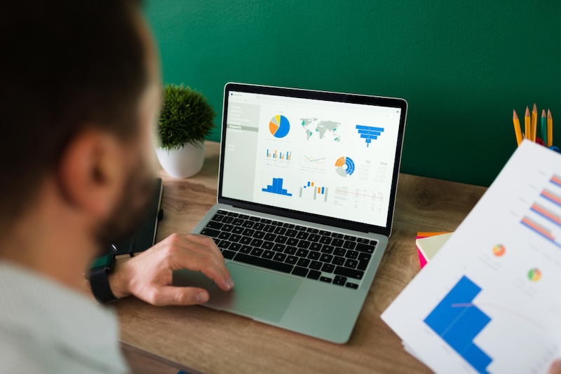 Hands pointing at a pay-per-click performance graph on a table.