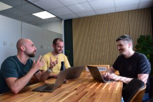 three seo experts sat at a table talking and smiling in a meeting room
